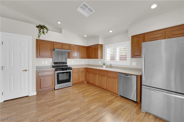 kitchen with visible vents, under cabinet range hood, a sink, appliances with stainless steel finishes, and light countertops