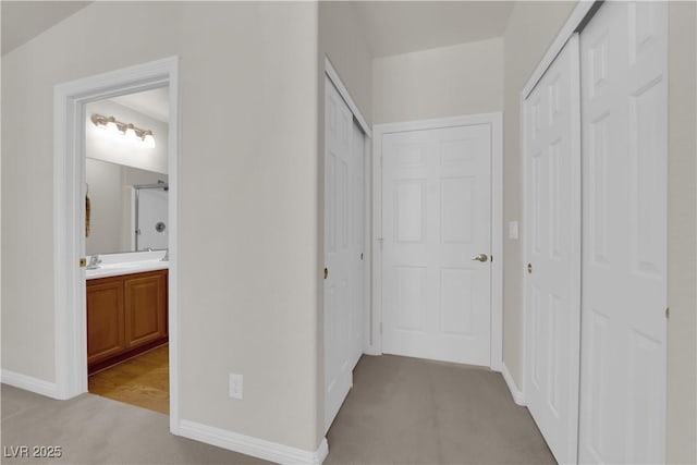 hall with light colored carpet and baseboards