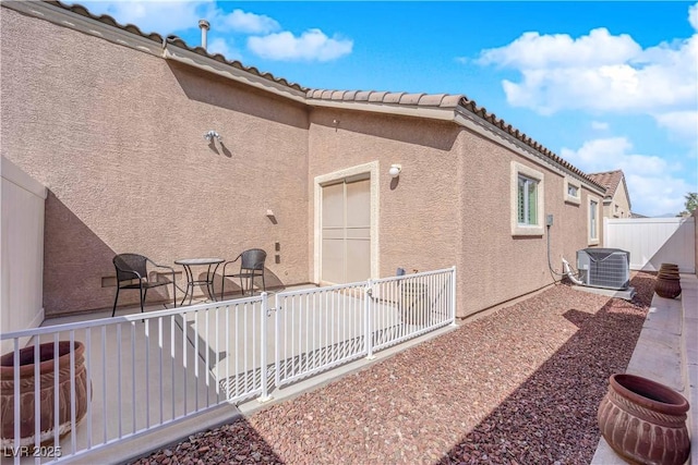 exterior space featuring a patio area, stucco siding, central AC, and fence