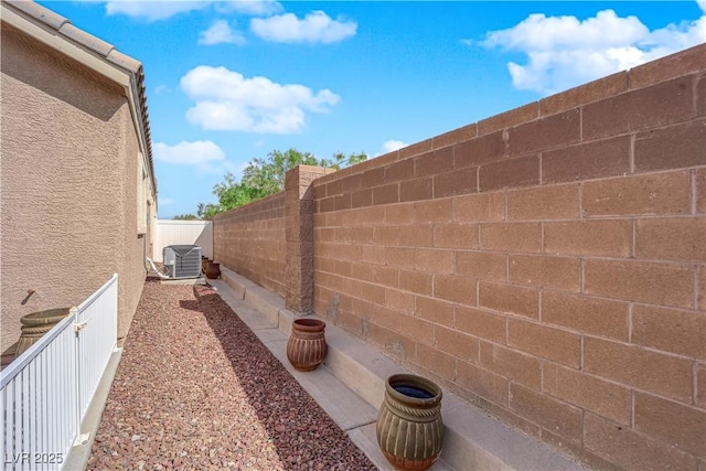 view of side of home with central AC unit and a fenced backyard