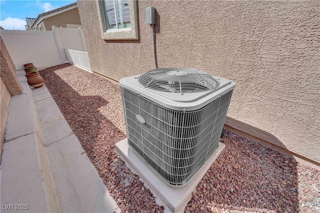 details with central air condition unit, fence, and stucco siding