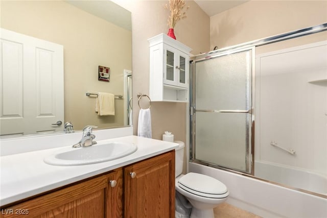 full bath with vanity, toilet, and bath / shower combo with glass door