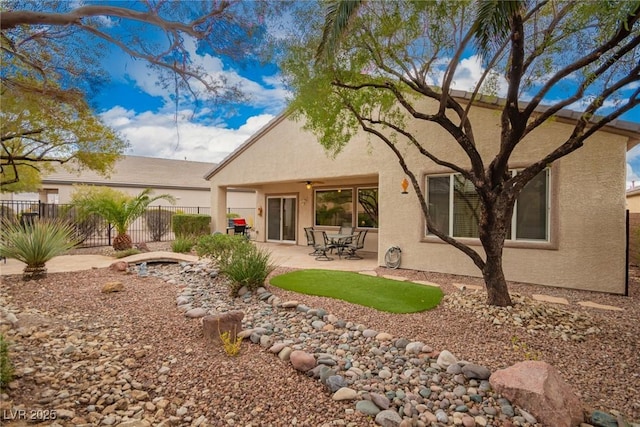 rear view of house with stucco siding, a patio, and fence