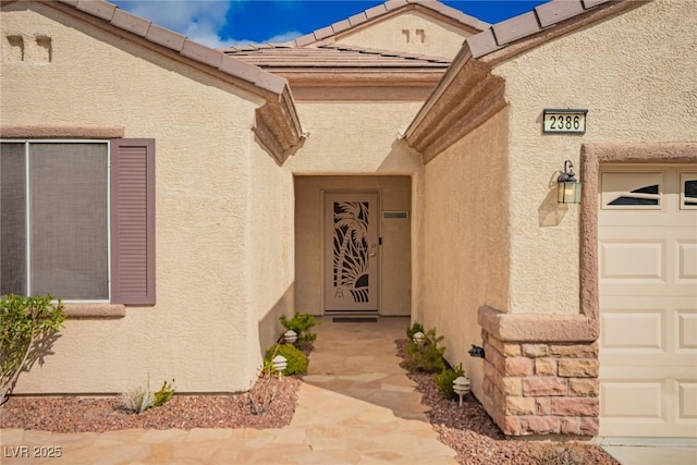 doorway to property featuring stucco siding and a garage