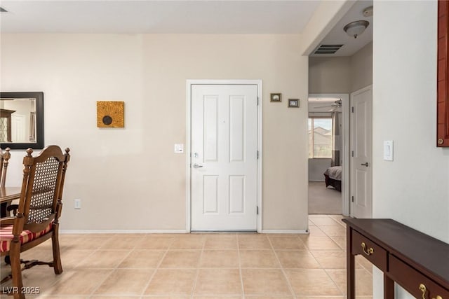 foyer entrance featuring light tile patterned floors, visible vents, a ceiling fan, and baseboards