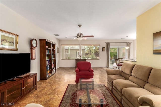 living area featuring light tile patterned floors, visible vents, baseboards, and ceiling fan