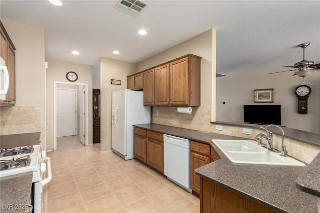 kitchen with white appliances, dark countertops, visible vents, and a sink