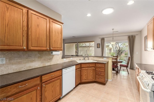 kitchen with white appliances, a peninsula, a sink, brown cabinets, and backsplash