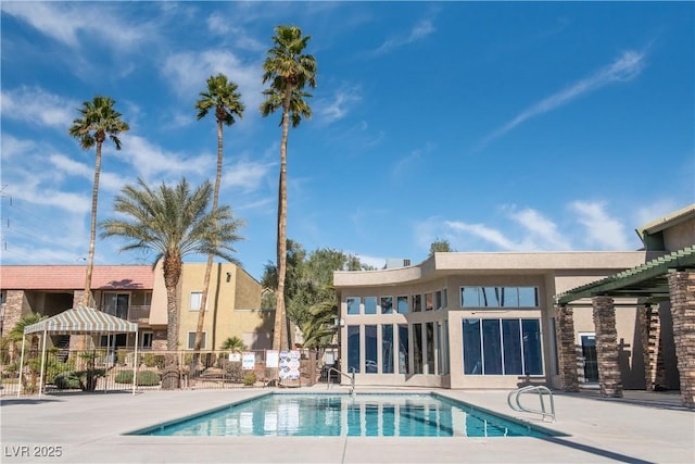 community pool with a patio and fence