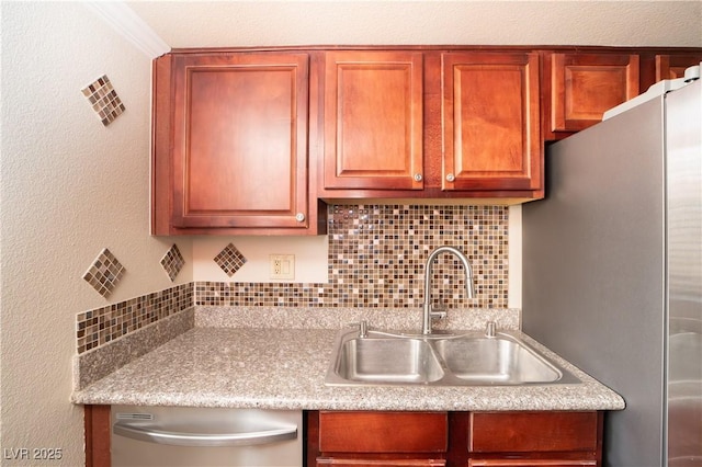 kitchen featuring light countertops, decorative backsplash, a textured wall, stainless steel appliances, and a sink