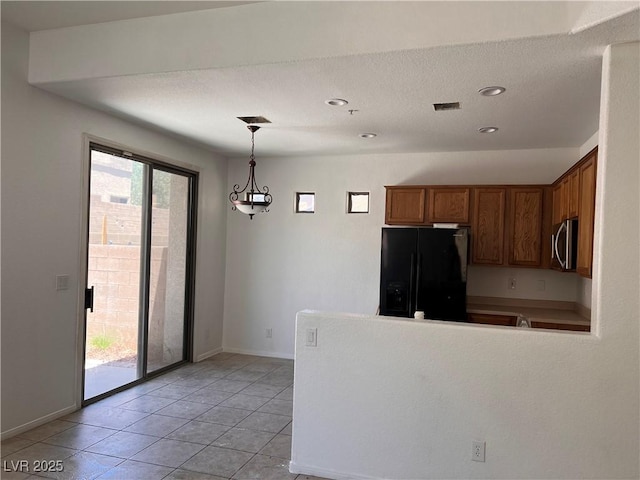 8301 Strawberry Spring St, Las Vegas, NV 89143 - kitchen featuring black fridge with ice dispenser, stainless steel microwave, brown cabinets, a peninsula, and hanging light fixtures