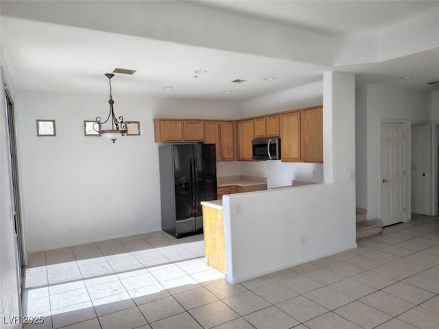 8301 Strawberry Spring St, Las Vegas, NV 89143 - kitchen featuring black fridge, stainless steel microwave, brown cabinets, light tile patterned floors, and a peninsula