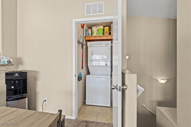 clothes washing area featuring visible vents, baseboards, carpet, stacked washer and dryer, and laundry area