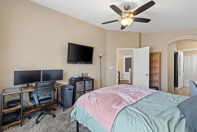 carpeted bedroom with visible vents, arched walkways, and ceiling fan