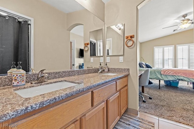 ensuite bathroom featuring tile patterned flooring, ensuite bath, lofted ceiling, and a sink