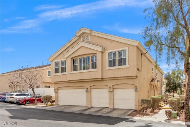 view of property with stucco siding, an attached garage, and fence