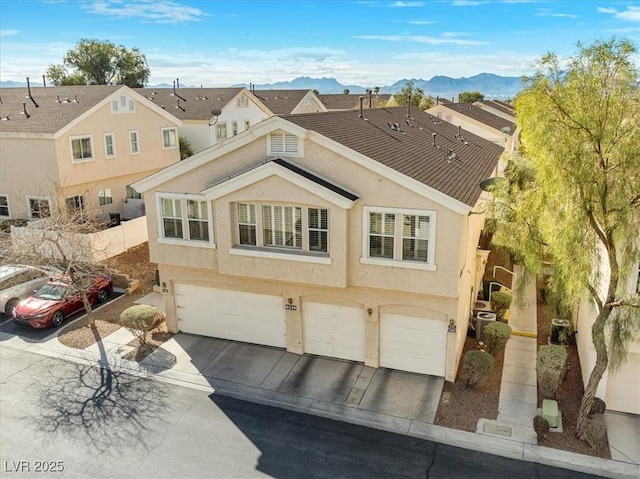 view of front facade featuring stucco siding, a mountain view, concrete driveway, and a garage