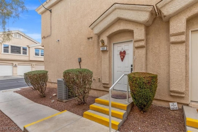 entrance to property with central AC unit and stucco siding