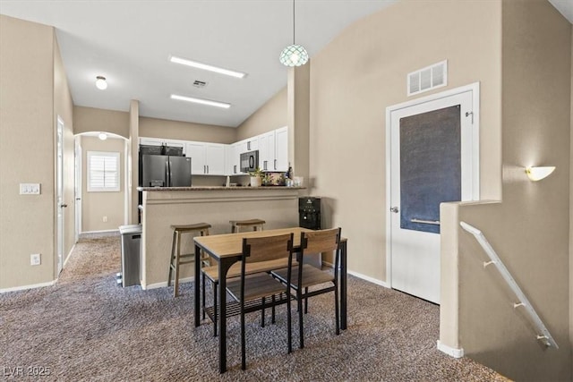 dining room with arched walkways, visible vents, baseboards, and carpet