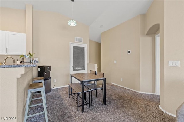 carpeted dining room with baseboards, visible vents, high vaulted ceiling, arched walkways, and a sink