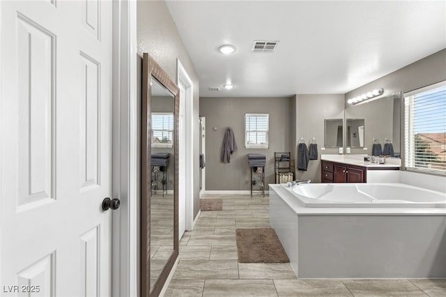 full bath with a wealth of natural light, visible vents, a garden tub, and vanity