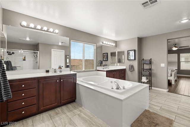 full bathroom with visible vents, two vanities, a sink, a shower stall, and a bath