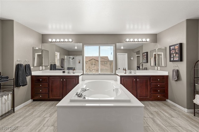 bathroom featuring a shower stall, two vanities, a garden tub, and a sink