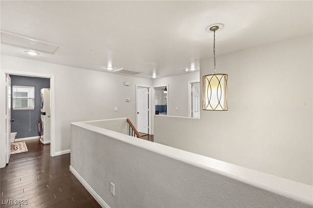 hallway with an upstairs landing, visible vents, dark wood-type flooring, and baseboards