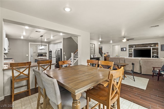 dining room featuring stairs, wood finished floors, visible vents, and a ceiling fan