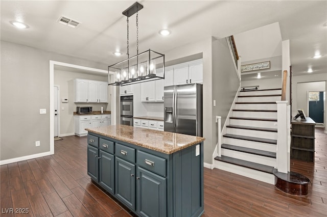 kitchen with white cabinets, appliances with stainless steel finishes, a center island, and dark wood-type flooring