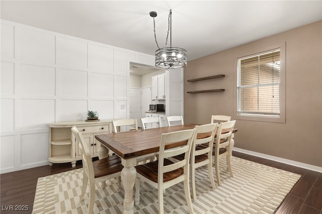 dining area with baseboards, dark wood-type flooring, and a decorative wall