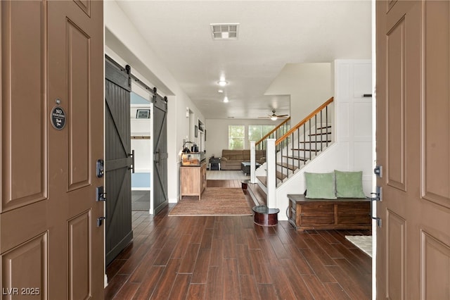 entrance foyer featuring stairs, a barn door, visible vents, and wood tiled floor