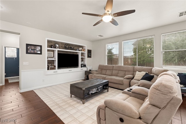 living room featuring visible vents, wainscoting, a ceiling fan, and wood finished floors