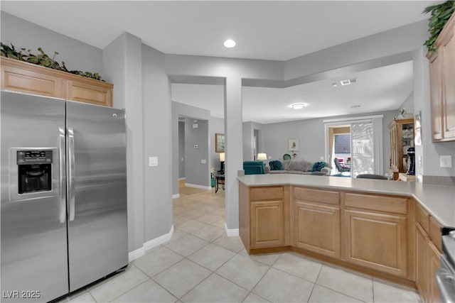 kitchen featuring open floor plan, light countertops, a peninsula, stainless steel refrigerator with ice dispenser, and light tile patterned flooring