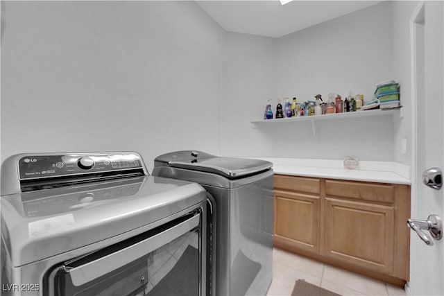 laundry area with light tile patterned floors, cabinet space, and washer and clothes dryer