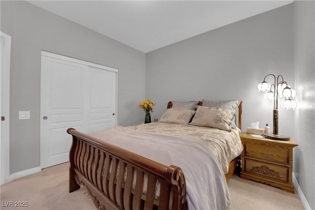 bedroom featuring a closet, light colored carpet, and baseboards