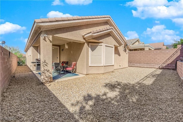 back of property with a patio area, stucco siding, and a fenced backyard