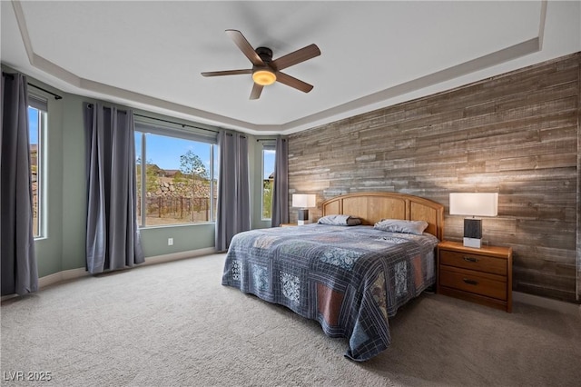 bedroom featuring a raised ceiling, carpet, baseboards, and ceiling fan