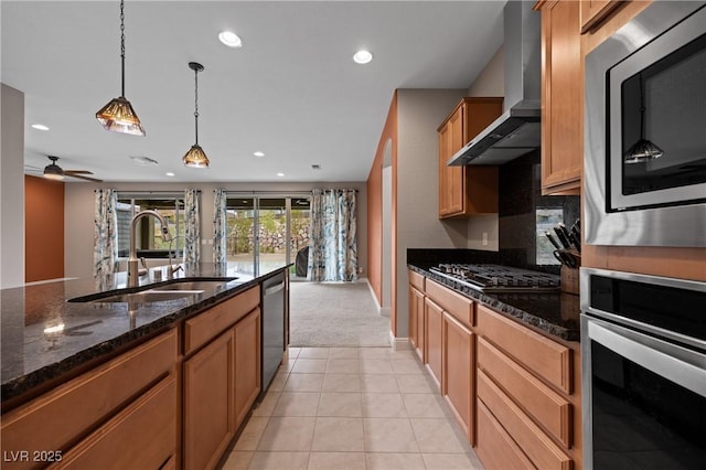 kitchen featuring pendant lighting, recessed lighting, appliances with stainless steel finishes, wall chimney exhaust hood, and a sink