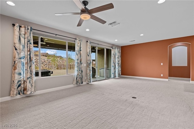 empty room with visible vents, recessed lighting, baseboards, and arched walkways