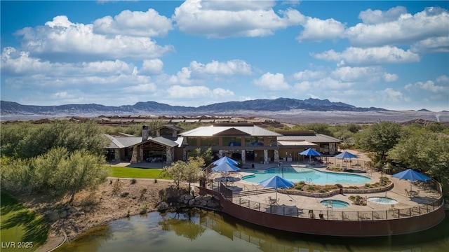 back of house featuring a mountain view, a community hot tub, a patio, and a community pool