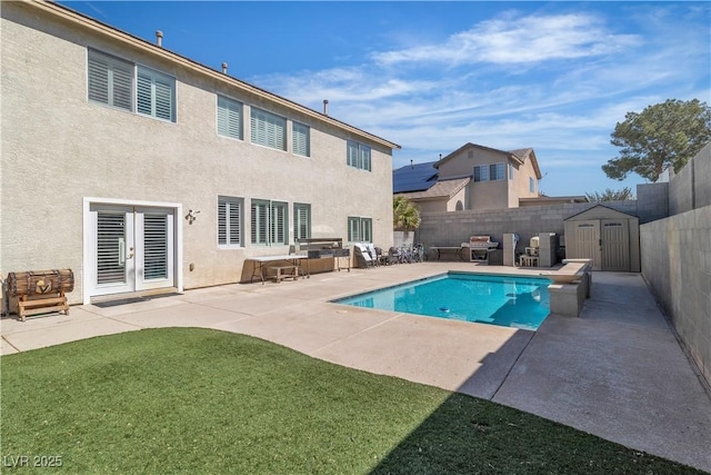 view of pool featuring a shed, french doors, a fenced backyard, an outbuilding, and a patio