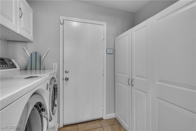 washroom featuring light tile patterned floors, cabinet space, and washing machine and clothes dryer