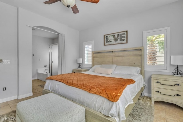 bedroom featuring a ceiling fan, light tile patterned floors, baseboards, and arched walkways