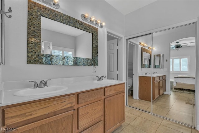 ensuite bathroom featuring a sink, ceiling fan, double vanity, and tile patterned flooring