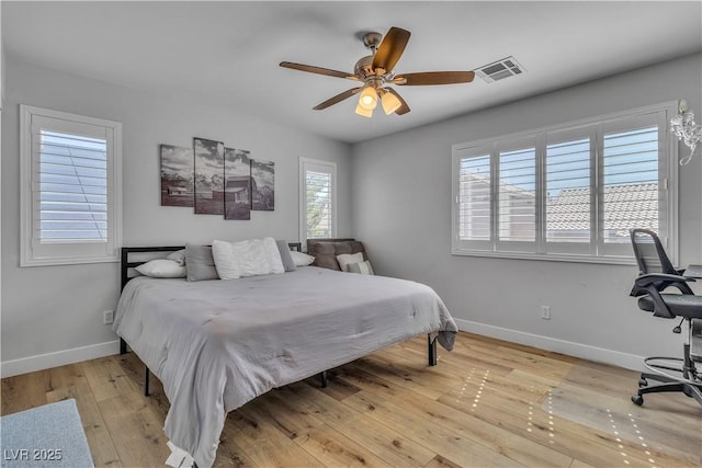 bedroom featuring visible vents, a ceiling fan, baseboards, and wood-type flooring