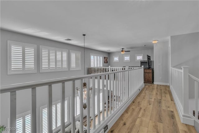 hall featuring visible vents, baseboards, and wood-type flooring