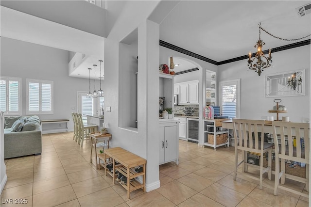 dining room with wine cooler, a notable chandelier, light tile patterned flooring, and ornamental molding