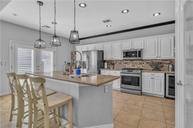 kitchen with a sink, a kitchen breakfast bar, white cabinetry, wine cooler, and appliances with stainless steel finishes