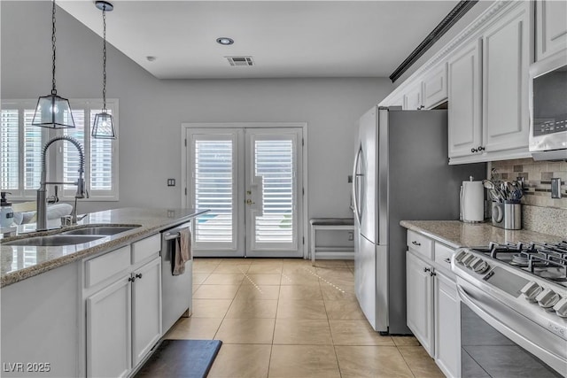 kitchen with a sink, stainless steel appliances, light tile patterned floors, and white cabinetry